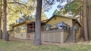 Eine Holzhütte mit überdachter Veranda, einer Treppe und einem eingezäunten Deckbereich.
