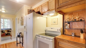 Une cuisine avec des meubles de rangement en bois, un réfrigérateur, une cuisinière et un évier.
