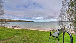 Un banc au bord d’un lac, avec une pelouse au premier plan et des arbres en arrière-plan.