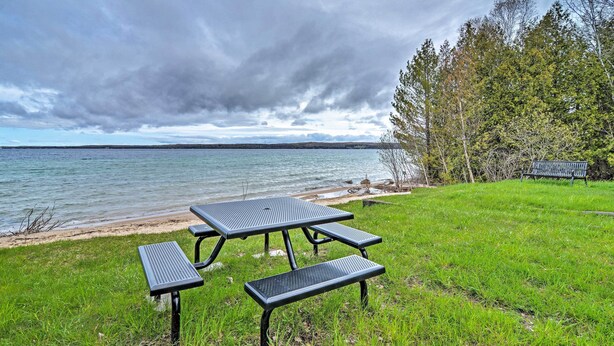 Une table de pique-nique installée sur une pelouse près d’une étendue d’eau, avec un banc et une assise de banc.