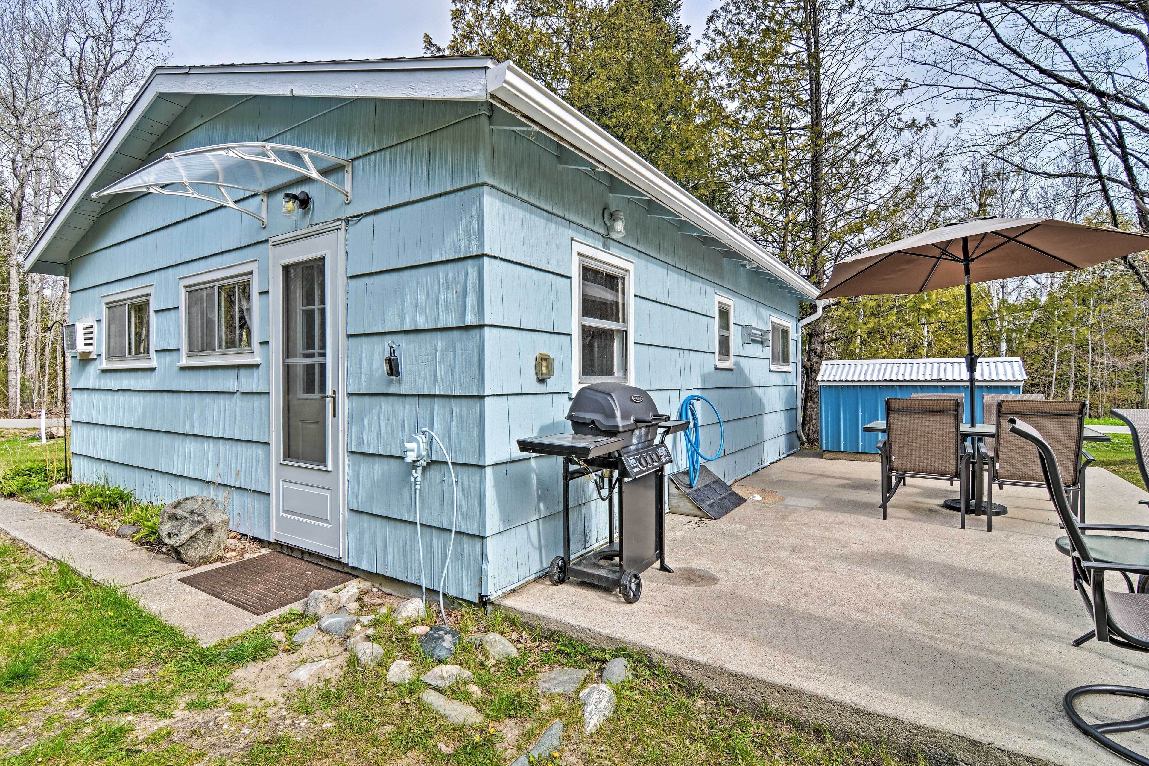 Una casa blu con un patio dotato di barbecue, posti a sedere all'aperto e un tubo da giardino.