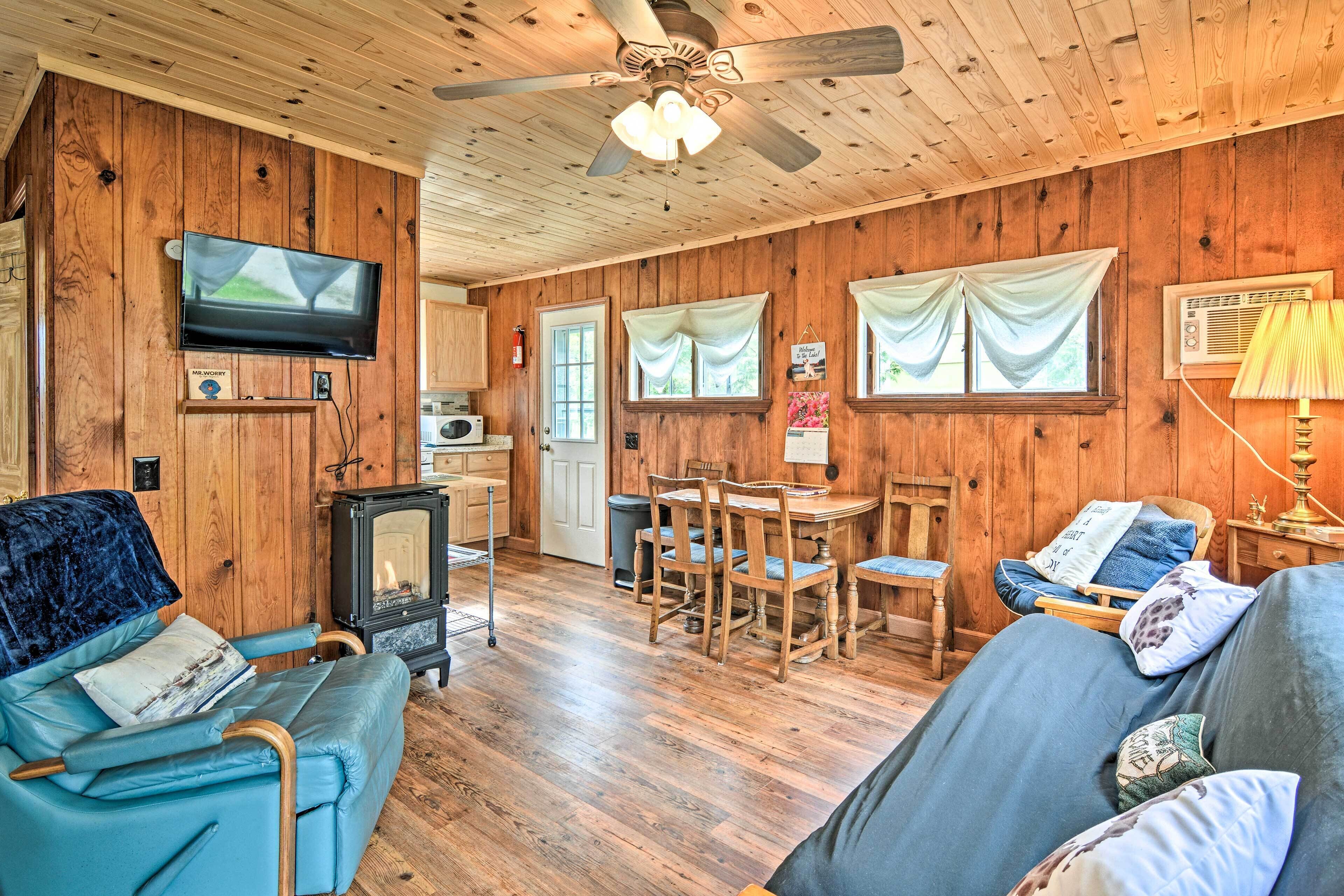 Un accogliente interno di una baita con arredamento in legno, una televisione a parete, un tavolo da pranzo con sedie e un divano.
