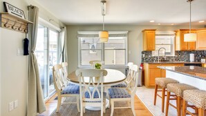 A modern kitchen with a round dining table, white chairs, and a central island with stools. - Avalon Vacation Rental w/ Porch & Grill! (Avalon)