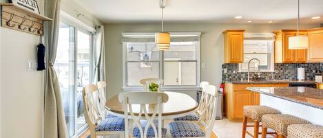 Una cocina moderna con una mesa de comedor redonda, sillas blancas y una isla central con taburetes.
