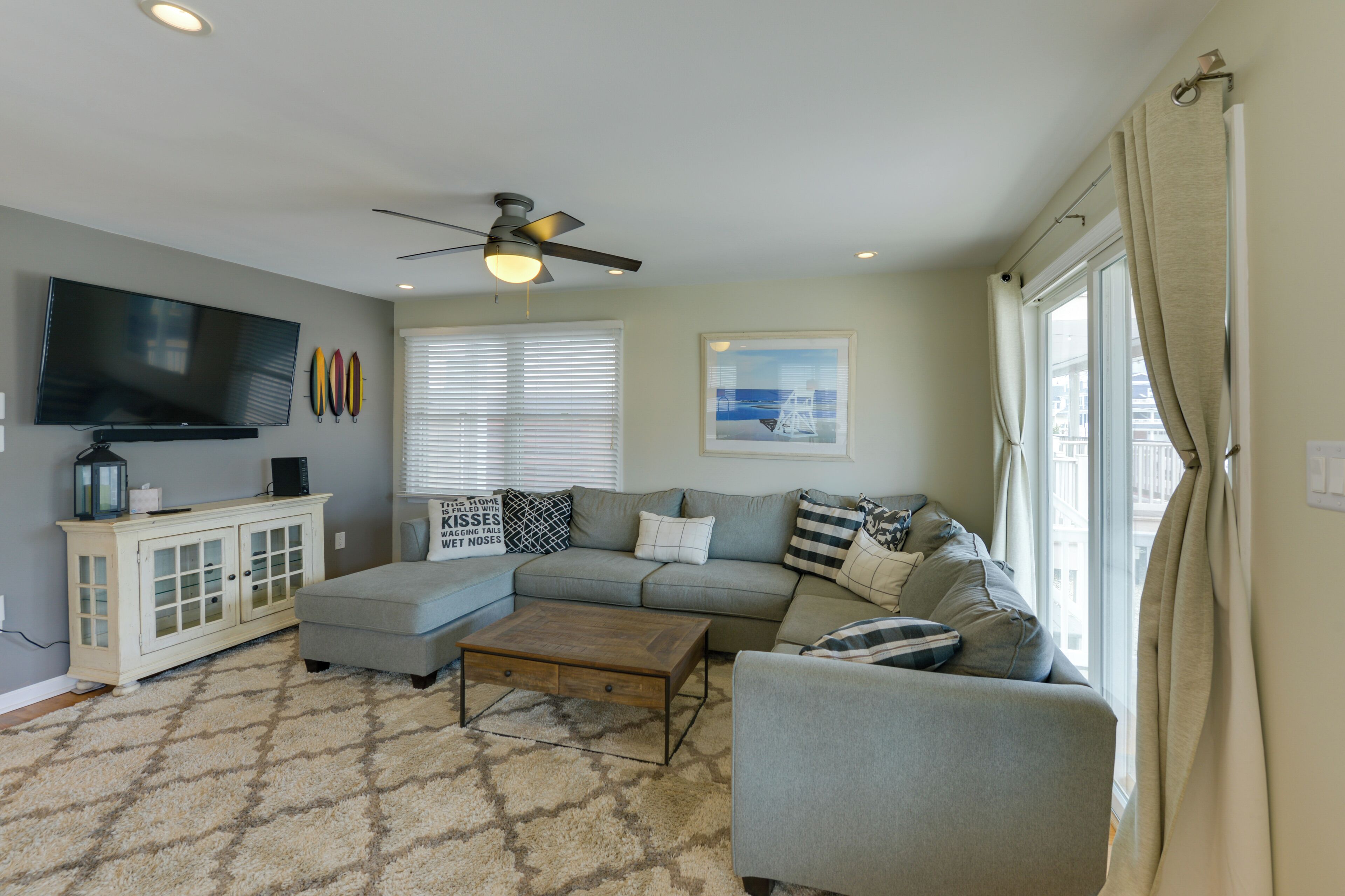 A living room with a sectional sofa, a coffee table, a TV, and a ceiling fan.