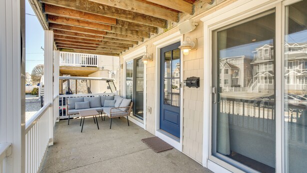 A covered porch with a seating area, a sliding glass door, and a view of neighboring houses. - Avalon Vacation Rental w/ Porch & Grill! (Avalon)