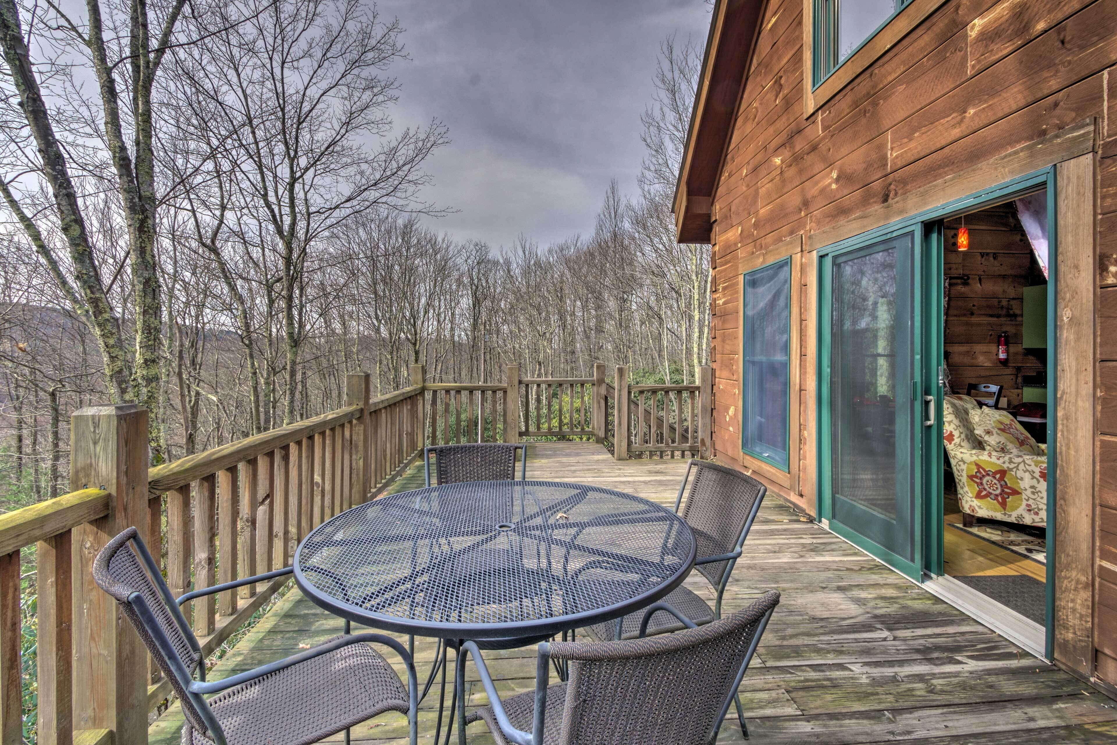 A wooden deck with a round table and chairs, a wooden fence, and a building with a sliding glass door.