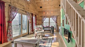 Interior de una cabaña de madera con comedor, sofá y escalera.