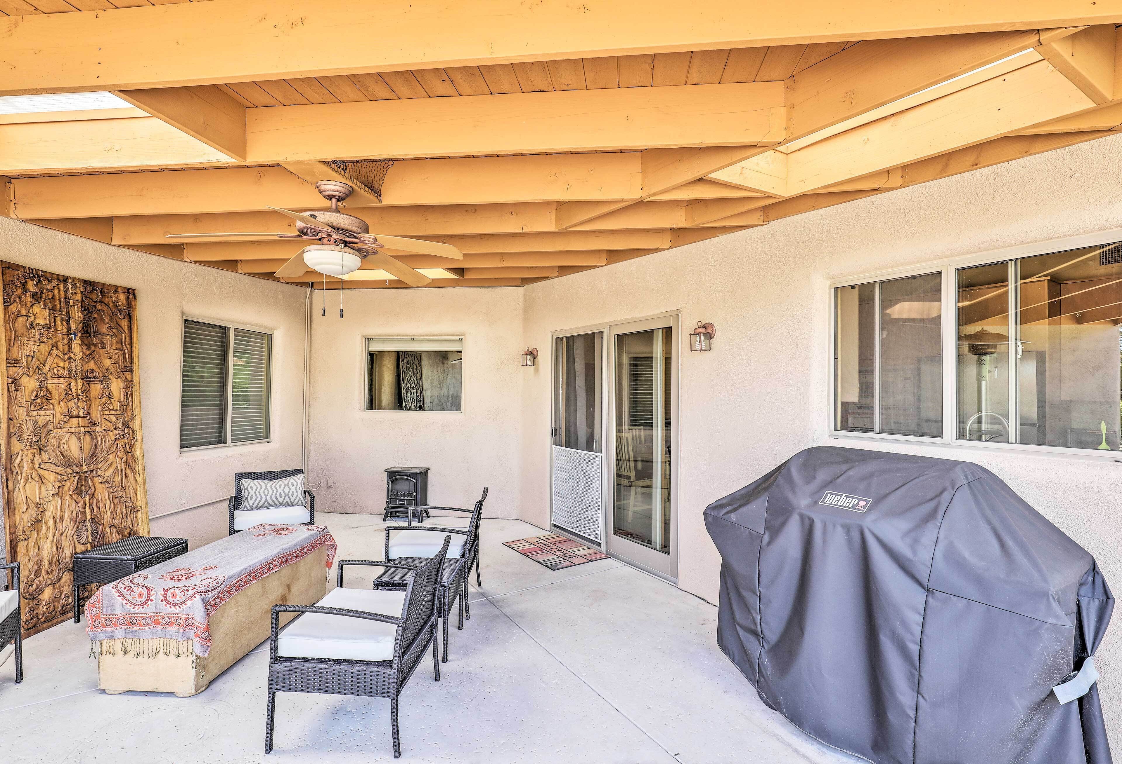 An outdoor patio with a covered grill, wicker furniture, and a ceiling fan.