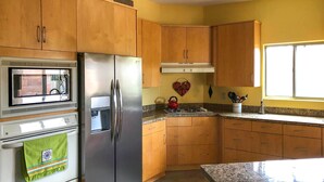 A kitchen with wooden cabinets, a stainless steel refrigerator, a microwave, and a granite countertop. - Tucson Home w/ Patio - Near Outdoor Adventure (Tucson)