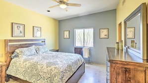 Un dormitorio con cama, ventilador de techo, cómoda y cuadros en la pared.