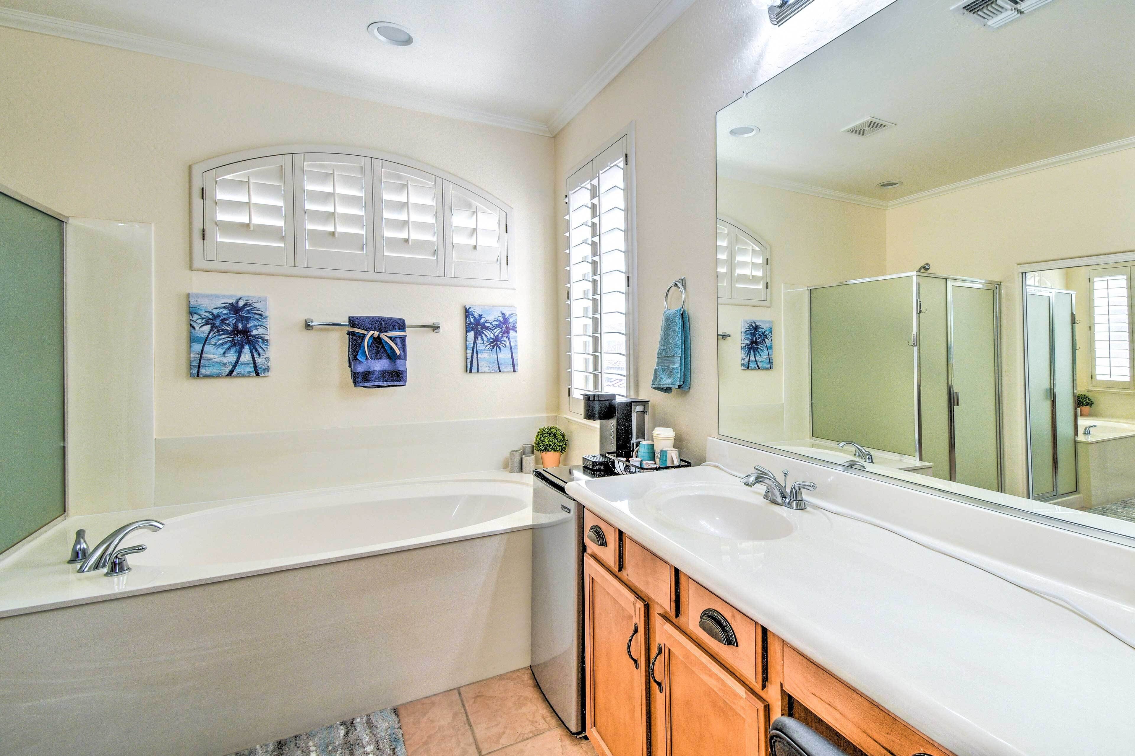 A modern bathroom with a double sink, a large mirror, and decorative palm paintings.