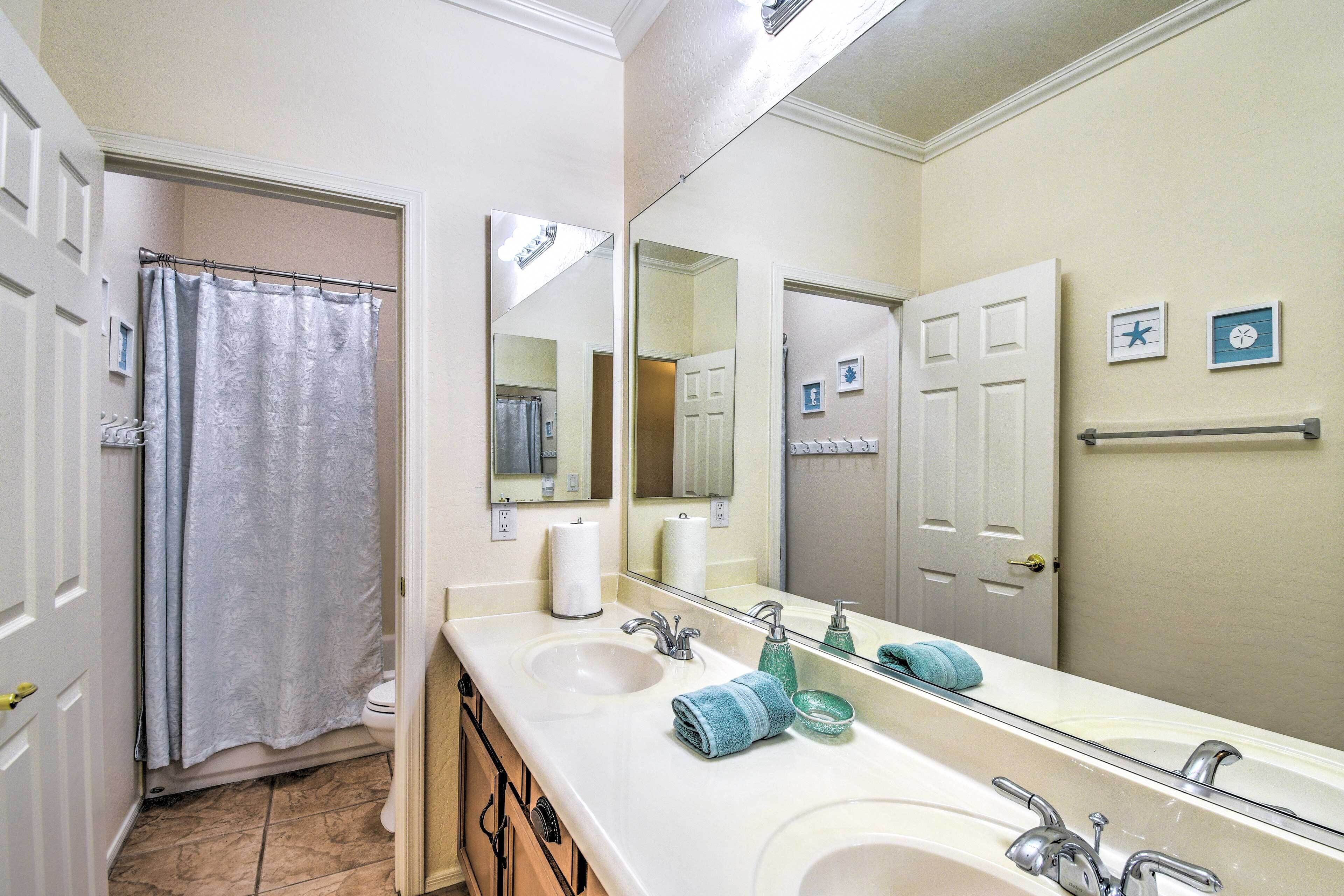 A bathroom with two sinks, a large mirror, a shower curtain, and a towel rack.