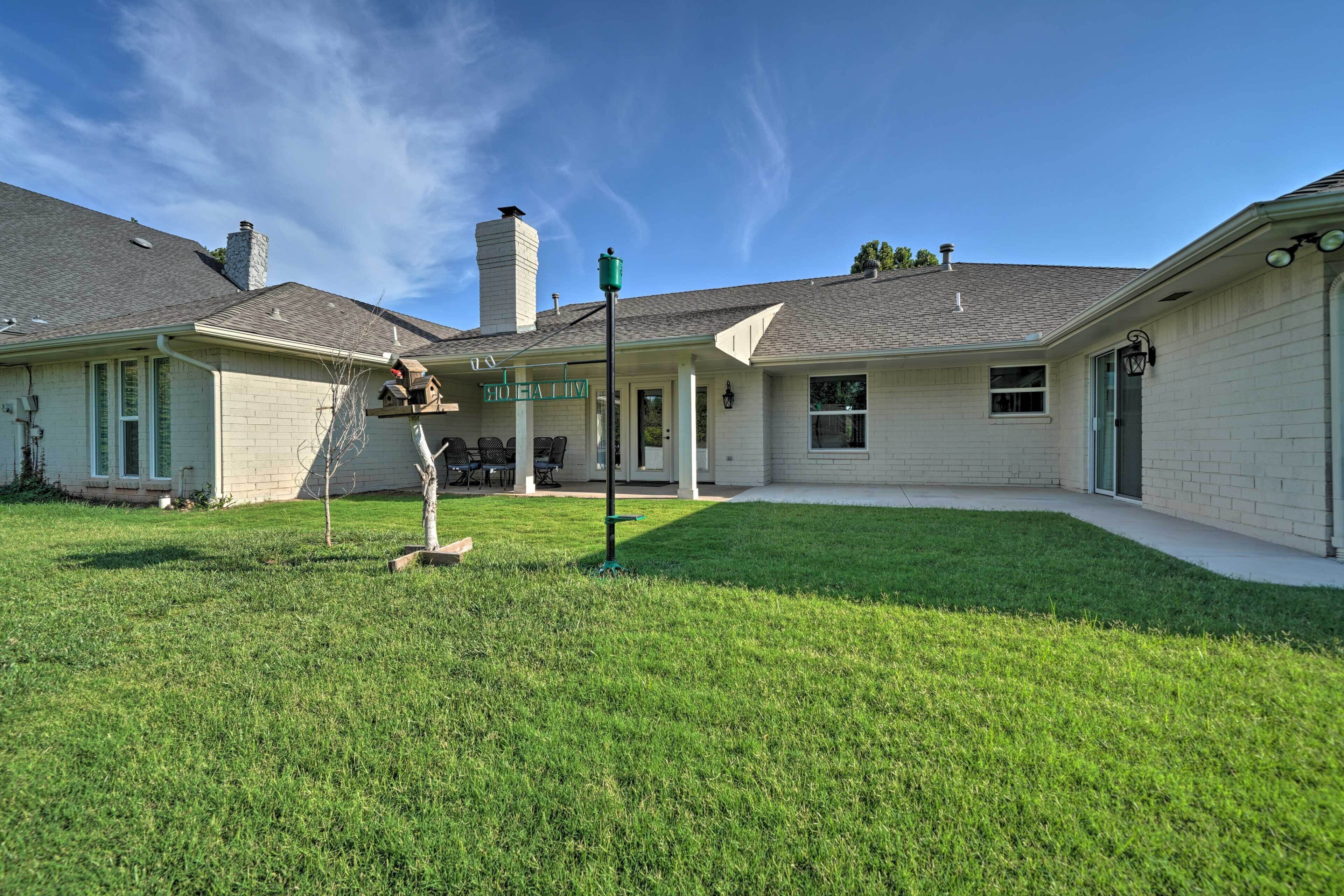 A two-story house with a covered patio, a chimney, and a well-maintained lawn.