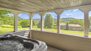 Un espace spa doté d’un jacuzzi et offrant une vue sur un paysage verdoyant grâce à de grandes fenêtres.