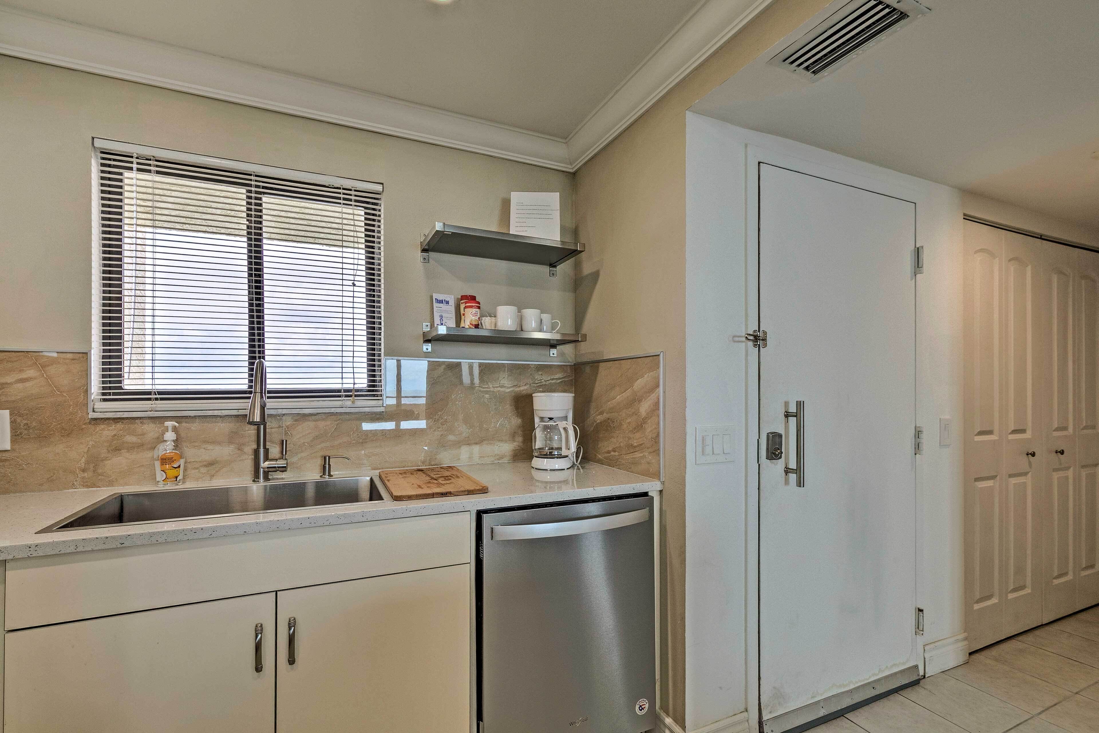 A kitchen with a stainless steel sink, a coffee maker, and a dishwasher.