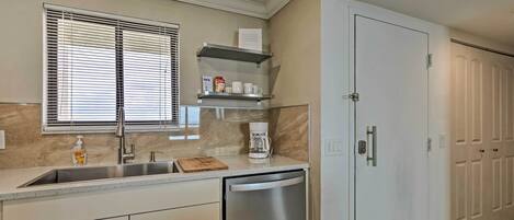 A kitchen with a stainless steel sink, a coffee maker, and a dishwasher.