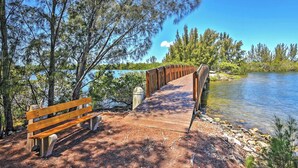 A wooden bridge leading to a bench by a lake surrounded by trees. - Private Beach Access: Hudson Resort Condo! (Hudson)