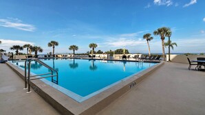 A rectangular swimming pool with a metal ladder on one side, surrounded by lounge chairs and palm trees. - Private Beach Access: Hudson Resort Condo! (Hudson)