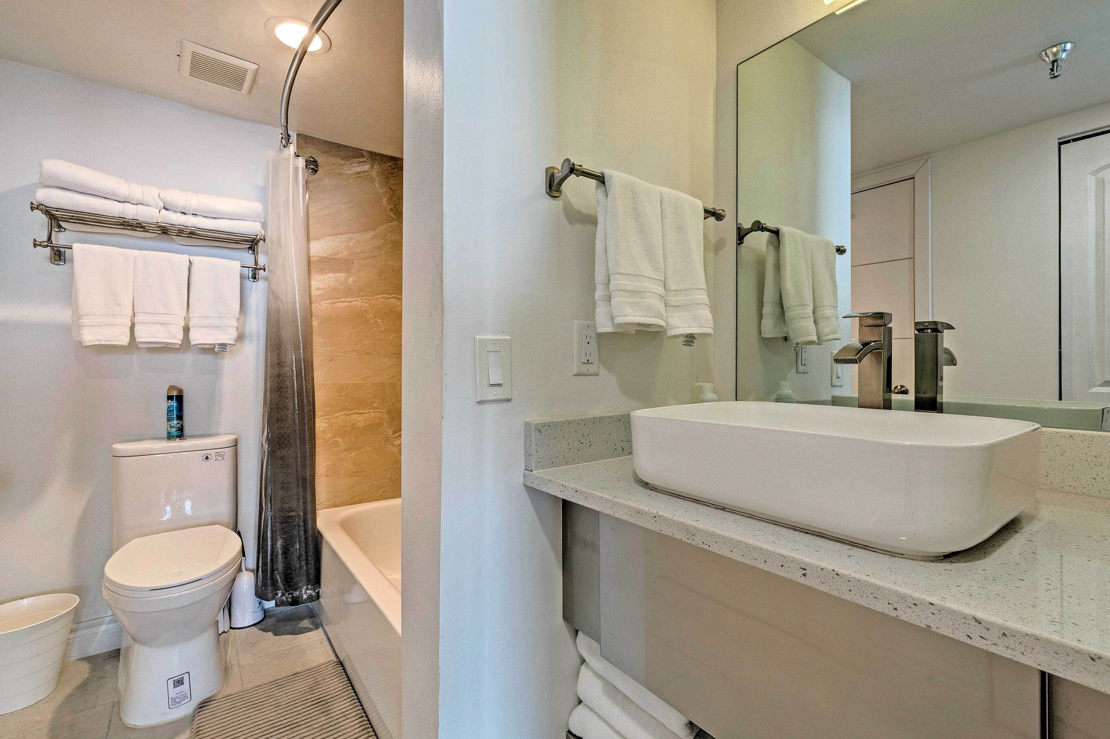 A modern bathroom with a toilet, shower, and sink.