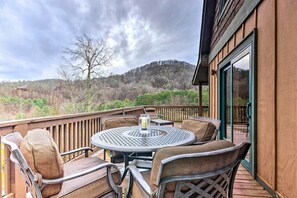 A wooden deck with a round table and chairs, a glass pitcher, and a view of a forested hillside. - Mountain Cabin w/ Fire Pit, Walk to Golf & Fishing (Vilas)