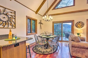 A dining area with a round table, chairs, and a chandelier. There is a clock on the wall and a sofa in the background. - Mountain Cabin w/ Fire Pit, Walk to Golf & Fishing (Vilas)