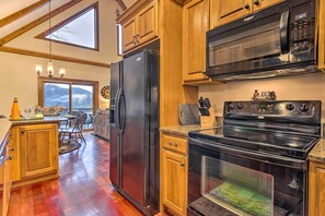 A kitchen with wooden cabinets, a black refrigerator, a microwave, and a stove. - Mountain Cabin w/ Fire Pit, Walk to Golf & Fishing (Vilas)