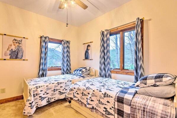 A bedroom with two beds, a ceiling fan, and large windows with curtains. - Mountain Cabin w/ Fire Pit, Walk to Golf & Fishing (Vilas)