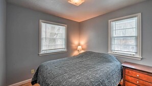 A bedroom with a bed, two windows with blinds, a ceiling light, and a wooden dresser. - Spacious Irwin Home on Snake River! (Irwin)