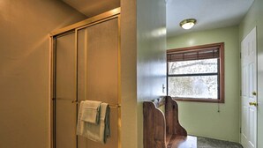 A bathroom with a shower, a towel rack, a window, and a door. - Spacious Irwin Home on Snake River! (Irwin)