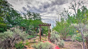 A garden with a wooden pergola, a red pathway, and various shrubs. - Taos Area Escape on 1.5 Acres: Panoramic Mtn Views (El Prado)