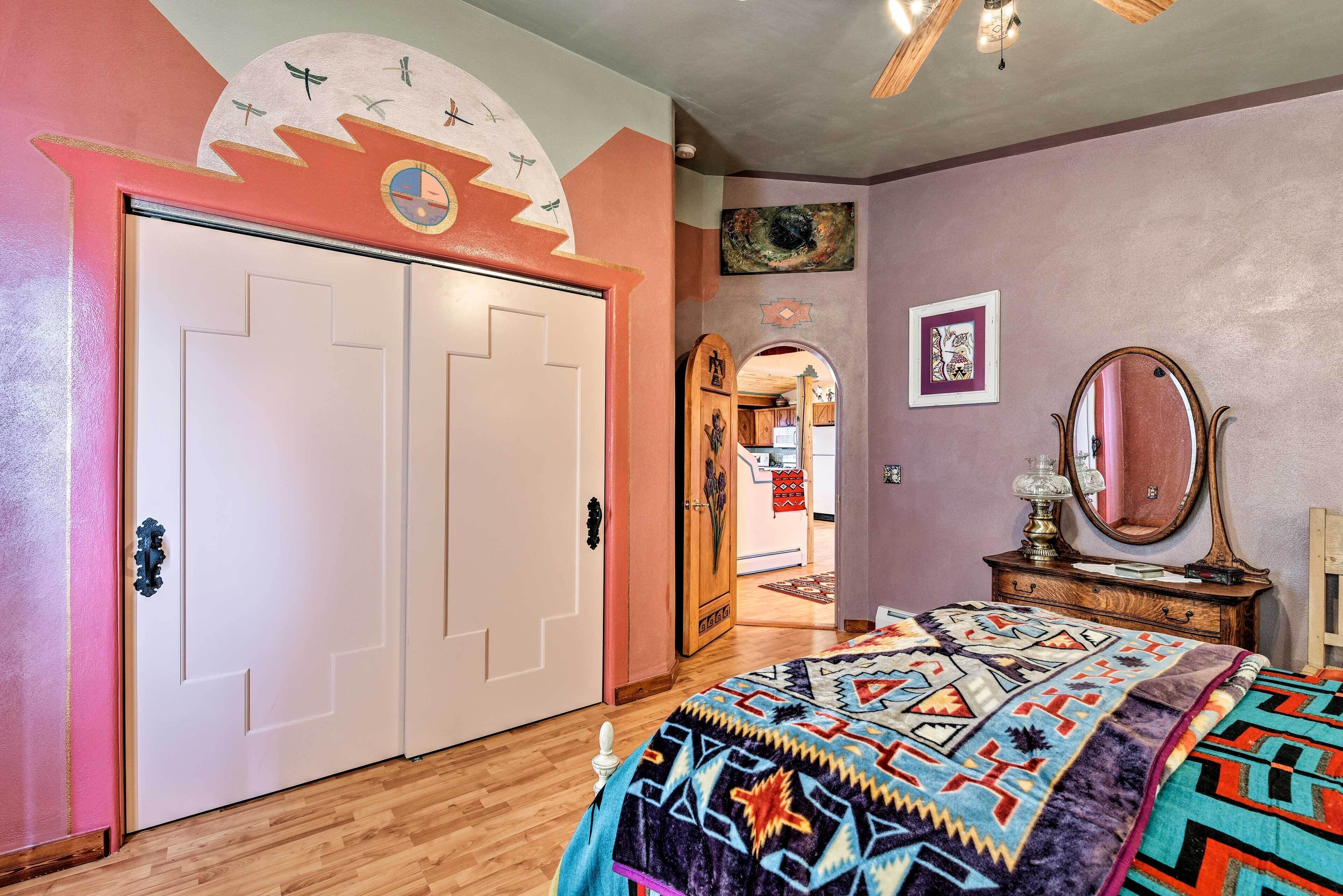 Ein Schlafzimmer mit einem großen Bett, einem Kleiderschrank, einem Spiegel und einer Tür mit dekorativem Design.