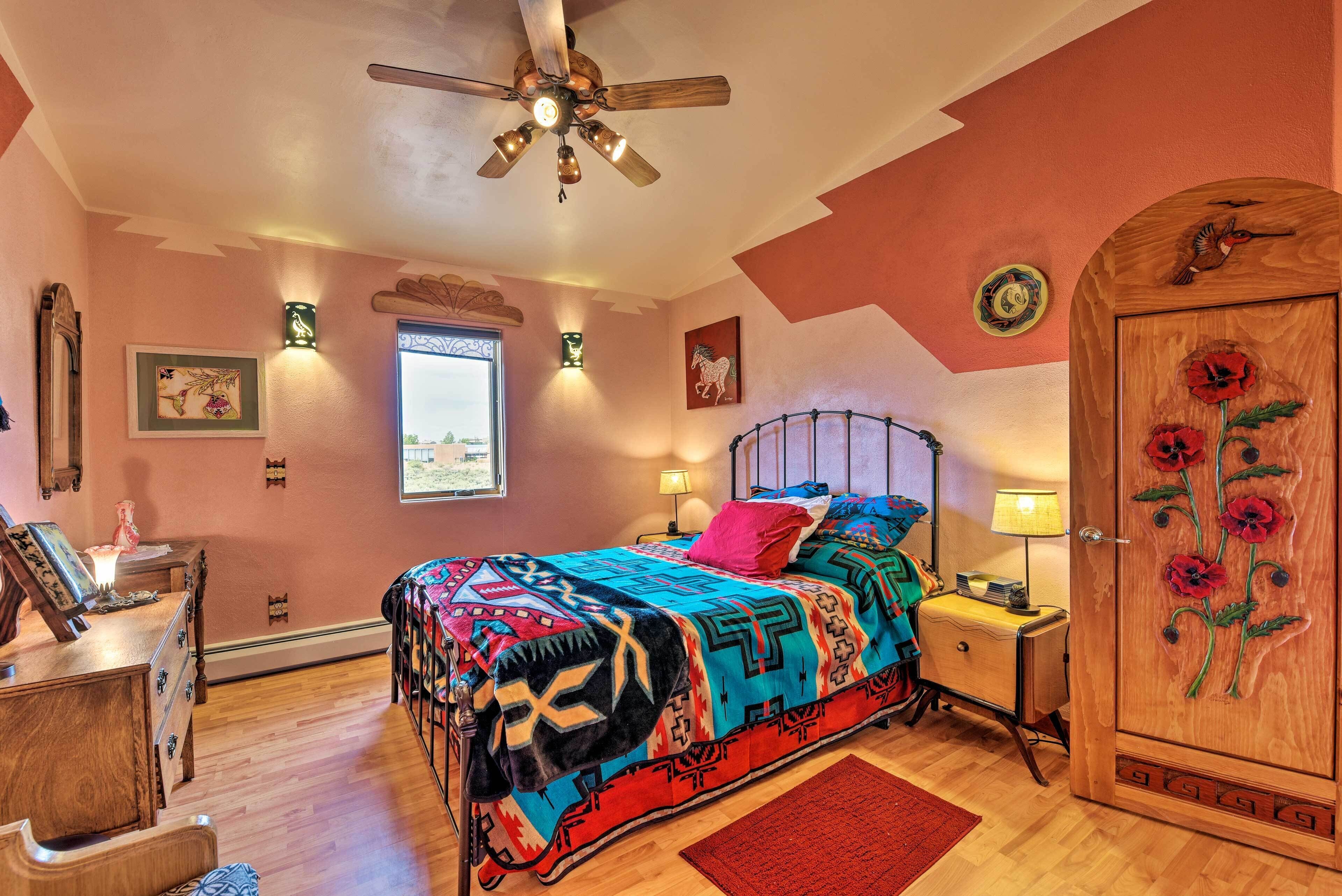A bedroom with a bed, a wooden wardrobe, a desk, a chair, a window, and a ceiling fan.