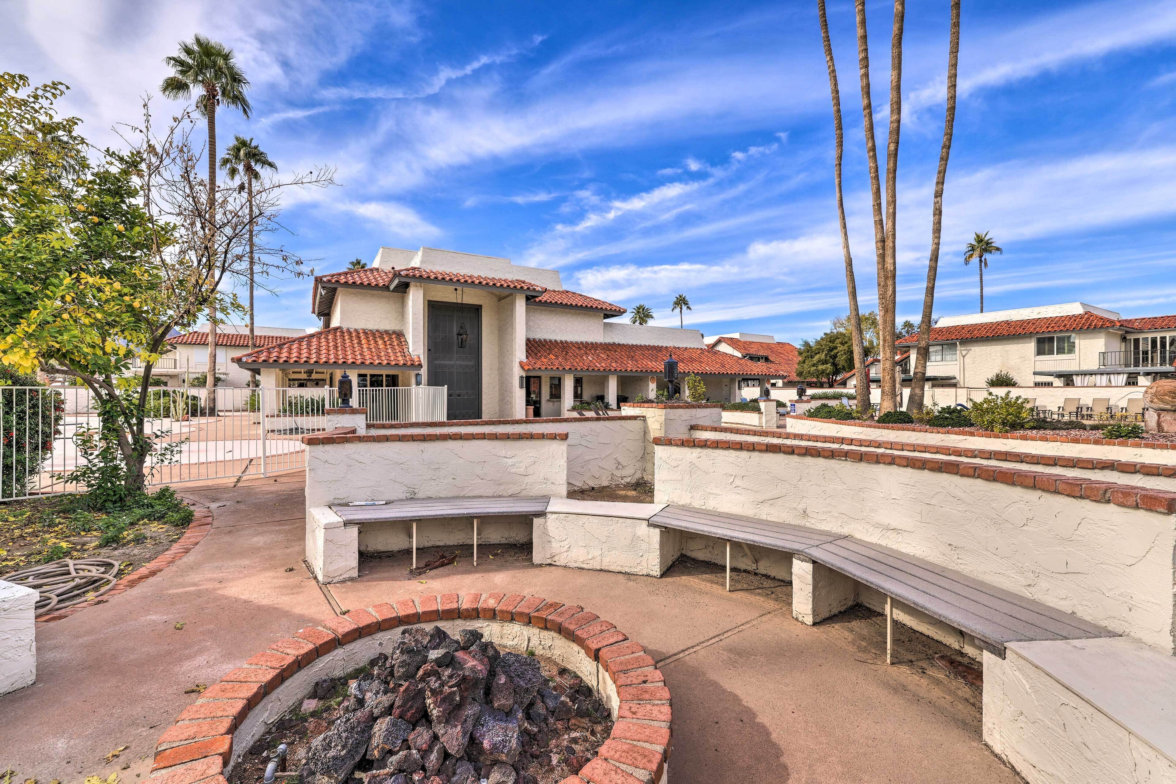 A courtyard with a fire pit, benches, and a building with a tiled roof.