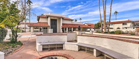A courtyard with a fire pit, benches, and a building with a tiled roof.