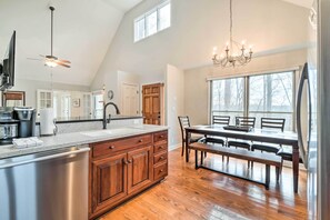 A spacious kitchen with a large island, wooden cabinets, and a dining area with a table and chairs. - Relax Poolside! Family Getaway in Nashville Area (Pegram)