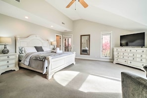 A spacious bedroom with a large bed, a dresser, a television, and a ceiling fan. - Relax Poolside! Family Getaway in Nashville Area (Pegram)