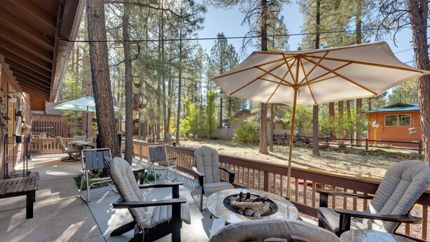 An outdoor patio with seating, a fire pit, and a large umbrella. - Deck + Fireplace: Cozy Pinetop Lakes Cabin! (Pinetop)