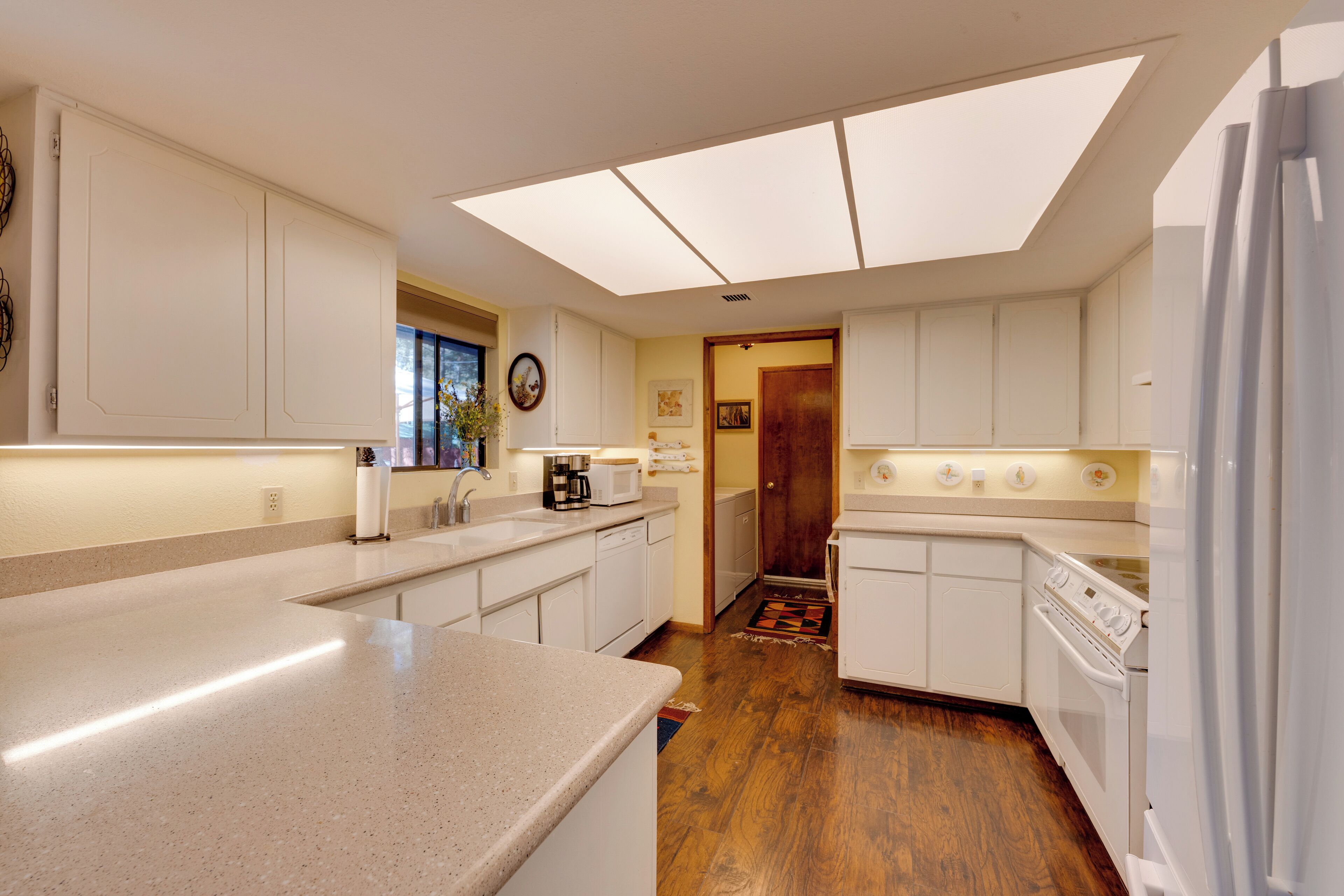 A modern kitchen with white cabinetry, a large island, and a skylight.