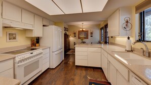 A kitchen with white cabinets, a stove, and a refrigerator. - Deck + Fireplace: Cozy Pinetop Lakes Cabin! (Pinetop)