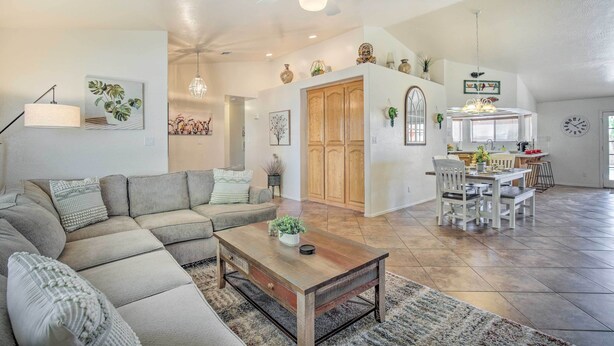 Een ruime woonkamer met een modulaire bank, een houten salontafel en een eethoek met een witte tafel en stoelen.