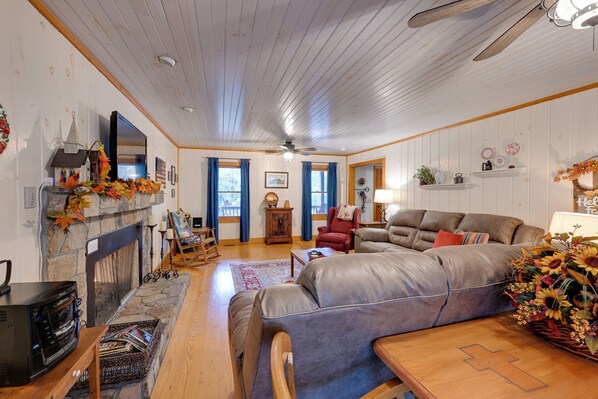 A cozy living room with a fireplace, a sofa, a red armchair, and a dining table.