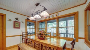 A wooden dining table with benches, surrounded by large windows.