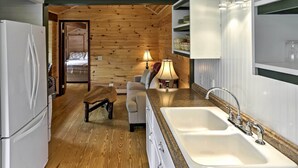 A compact kitchen with wooden walls, a sink, and a refrigerator. - Walk to Lake George! Bolton Landing Cottage (Bolton Landing)