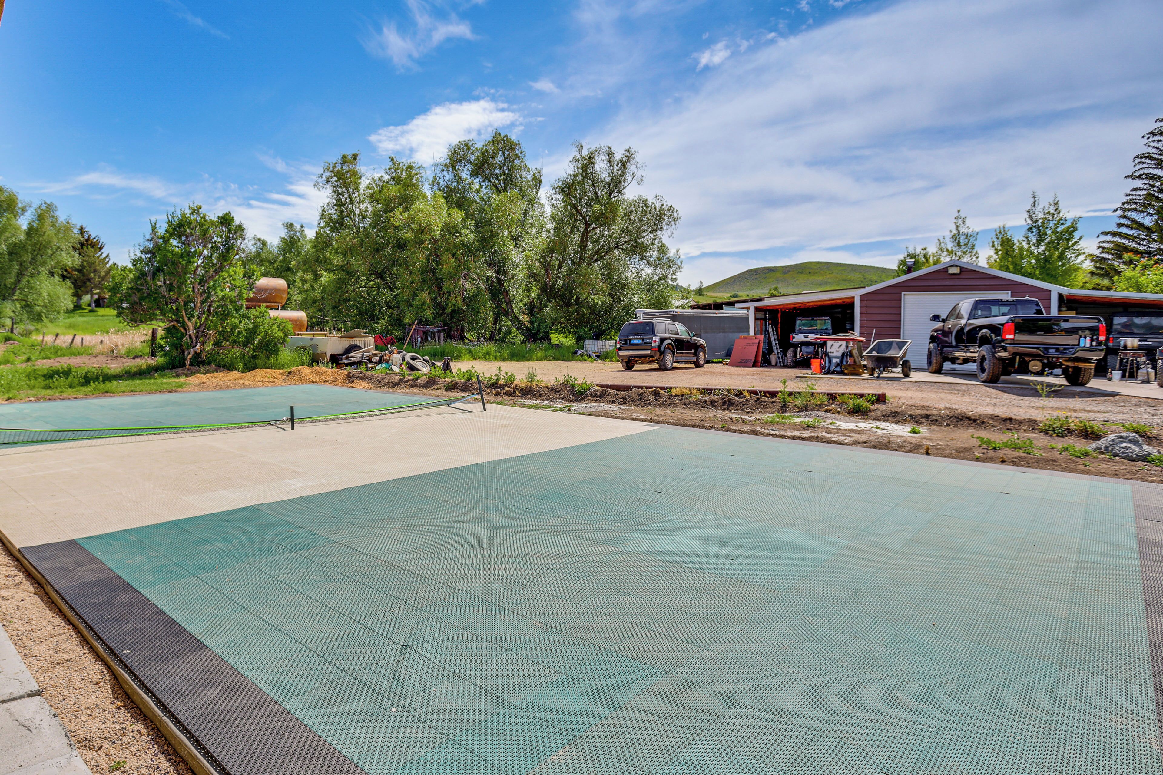 Ein Sportplatz mit grüner Spielfläche, umgeben von Bäumen und einem Gebäude mit einer Garage.