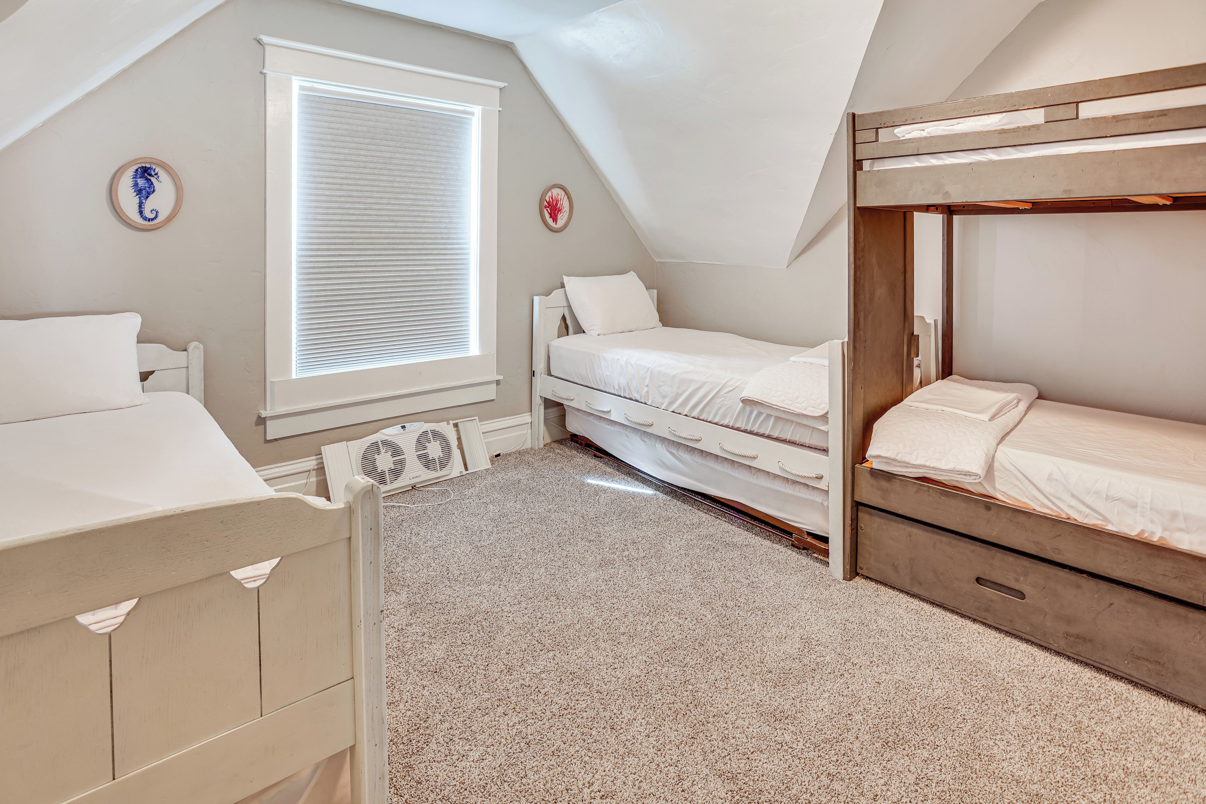 A bedroom with two bunk beds, a window with blinds, a radiator, and a small decorative seahorse on the wall.