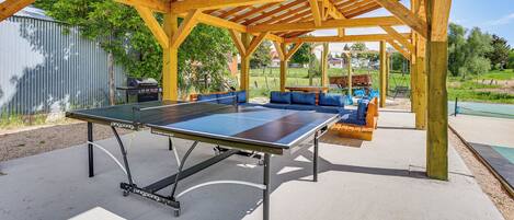 Ett bordtennisbord under en träbeklädd pergola med sittplatser.