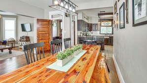 A spacious dining area with a long wooden table, chairs, and a central plant arrangement. - Charming Paris House ~ 1 1/2 Mi to Canyon! (Paris)