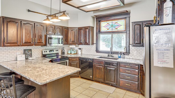 A kitchen with wooden cabinets, a stainless steel refrigerator, a built-in oven, and a large island with bar stools. - Charming Paris House ~ 1 1/2 Mi to Canyon! (Paris)