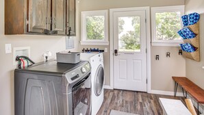 A laundry room with a washer and dryer, a bench, and a window with a view of trees. - Charming Paris House ~ 1 1/2 Mi to Canyon! (Paris)